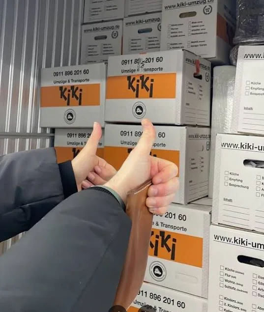 Umzugshelfer geben Daumen hoch im Lager mit Kartons