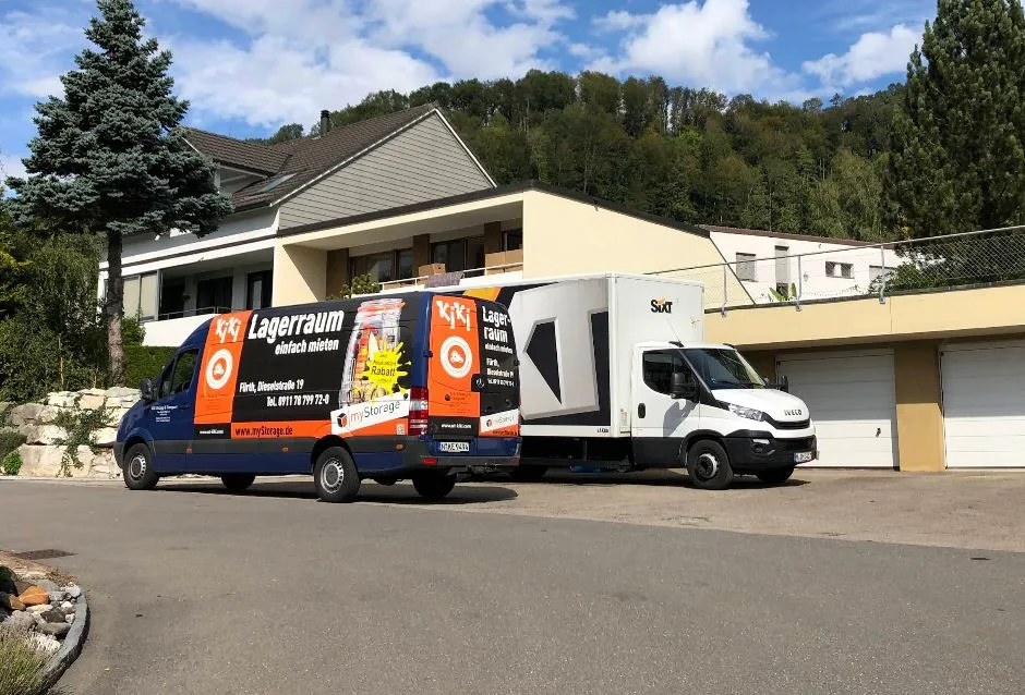 Zwei Umzugsfahrzeuge von KiKi Umzüge vor einem Wohngebäude